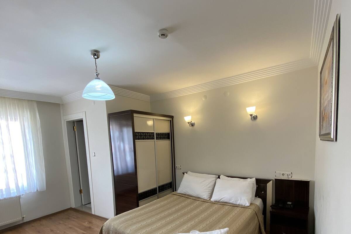 Un dormitorio con cama, mesitas de noche, armario y lámpara en el techo.