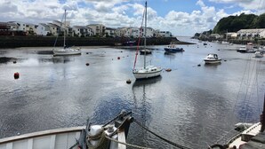 Un port où sont amarrés de nombreux bateaux, un mur de pierre et des bâtiments qui bordent la côte.