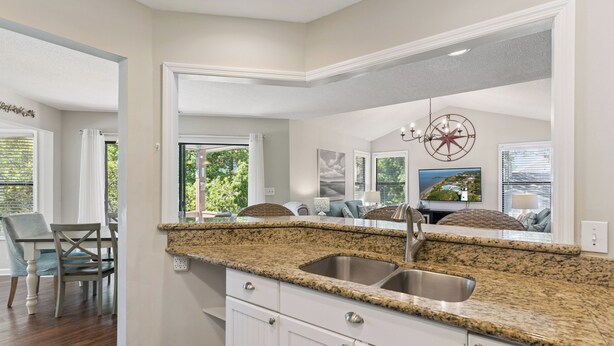 A kitchen with a granite countertop, white cabinets, and a stainless steel sink.