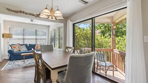 A dining area with a wooden table, chairs, and a view of the outdoors through large sliding glass doors.
