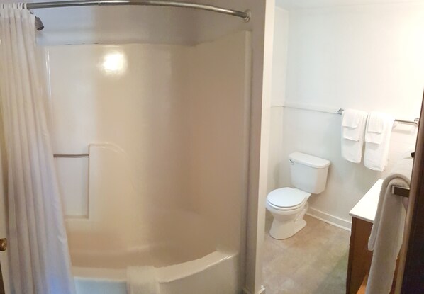 Un baño con ducha, inodoro y barra para toallas.