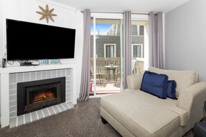 Een woonkamer met een open haard, een flatscreentelevisie en een bank met een kussen.