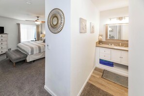 A bedroom with a bed, a bedside table, a lamp, and a ceiling fan.