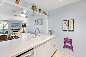 Une cuisine moderne avec des meubles blancs, un grand îlot central et un ventilateur de plafond.