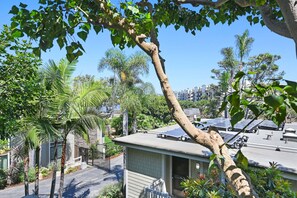 Un quartier résidentiel avec une maison dotée d’un toit recouvert de panneaux solaires, entourée de divers arbres et sous un ciel dégagé.