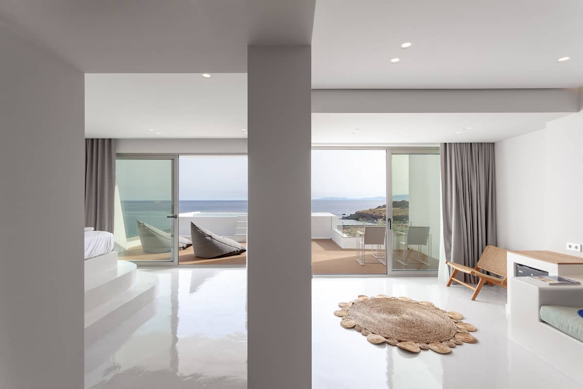 Una habitación de hotel moderna con balcón, un ventanal grande y vistas al océano.