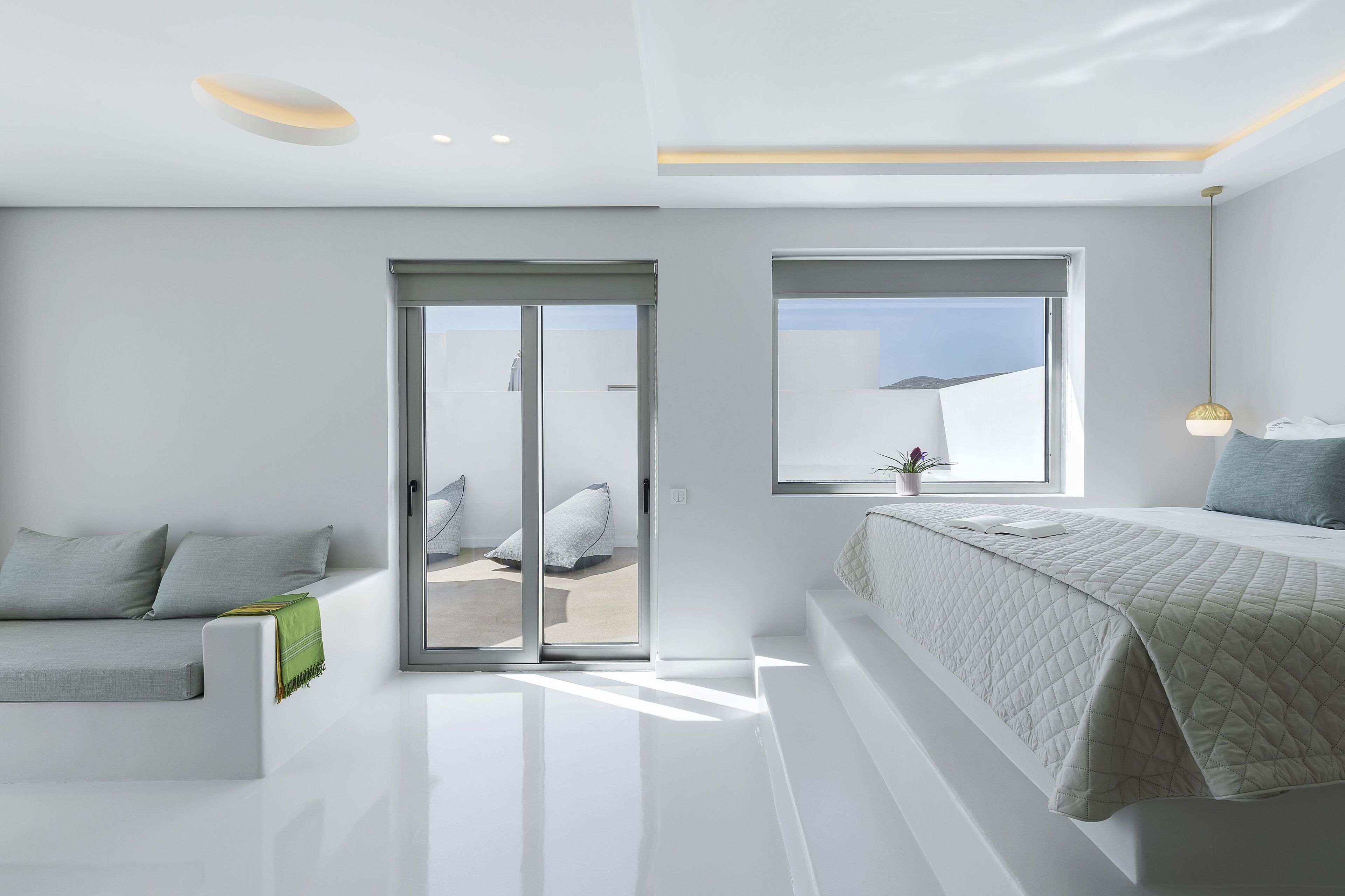 Une chambre moderne avec un lit, un canapé et une porte-fenêtre coulissante donnant sur un espace extérieur.