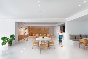 A modern, spacious living area with a round dining table, wooden chairs, and a sofa.