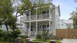 A two-story house with a balcony, a stone wall, and a wooden fence.