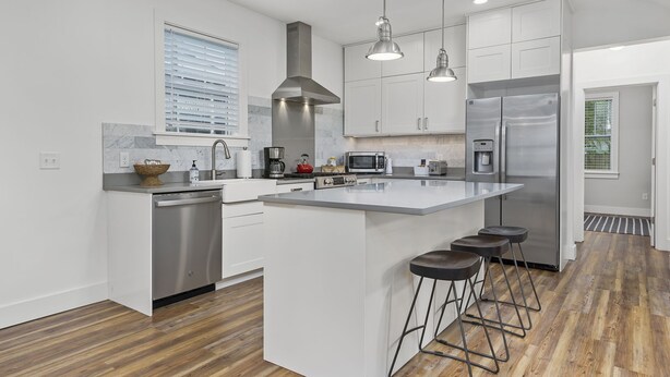A modern kitchen with white cabinetry, stainless steel appliances, and a central island with bar stools.