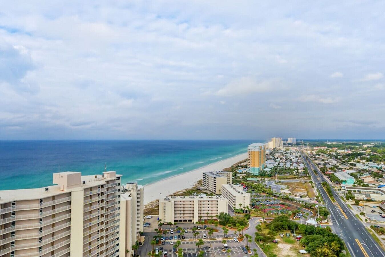 A coastal cityscape with a beach, high-rise buildings, and a road leading to the beach.