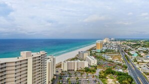 A coastal cityscape with a beach, high-rise buildings, and a road leading to the beach. - Sand Castle ~ 3-Story Beach Retreat with Heated Pool, Tiki Bar & Dual Game Rooms (Panama City Beach)