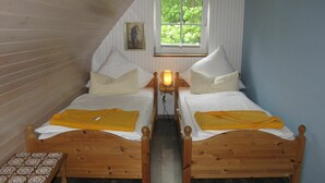 Una habitación pequeña y acogedora con dos camas de madera, un banco y una ventana.