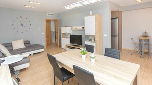 En moderne lejlighed med spiseområde, stue med sofa, TV og et køkken.
