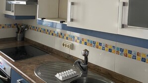Cocina con armarios blancos, un lavamanos de acero inoxidable y salpicadero de azulejos.