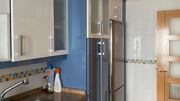 Una cocina moderna con armarios azules, un refrigerador de acero inoxidable y un salpicadero de azulejos.