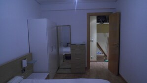 Un dormitorio con cama, cómoda, espejo y puerta que da a un baño.