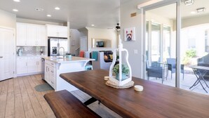A modern kitchen with white cabinets, a wooden island, and a dining area with a glass door leading outside. - Sun Haven At The Casitas In Sienna Hills 4 Bedroom Townhouse by RedAwning (Washington)