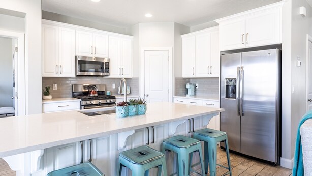 A modern kitchen with white cabinets, stainless steel appliances, and a central island with bar stools. - Sun Haven At The Casitas In Sienna Hills 4 Bedroom Townhouse by RedAwning (Washington)