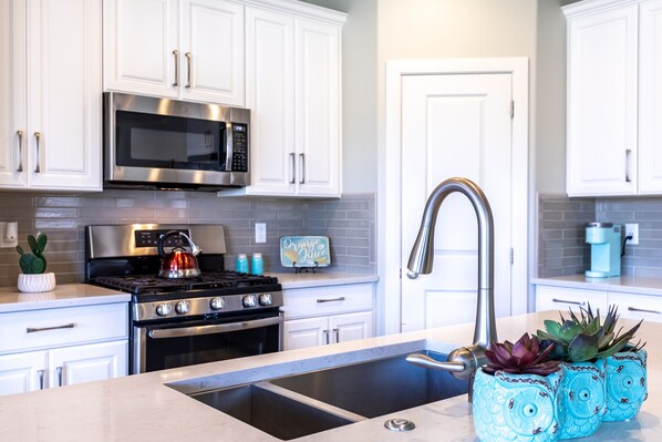 A modern kitchen with white cabinets, stainless steel appliances, and a built-in sink.