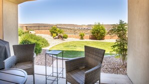 A patio with wicker chairs and a table, overlooking a landscaped yard with a fence and distant hills. - Sun Haven At The Casitas In Sienna Hills 4 Bedroom Townhouse by RedAwning (Washington)