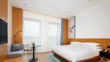 Una habitación de hotel moderna con una cama grande, un sofá, una mesita y un televisor.