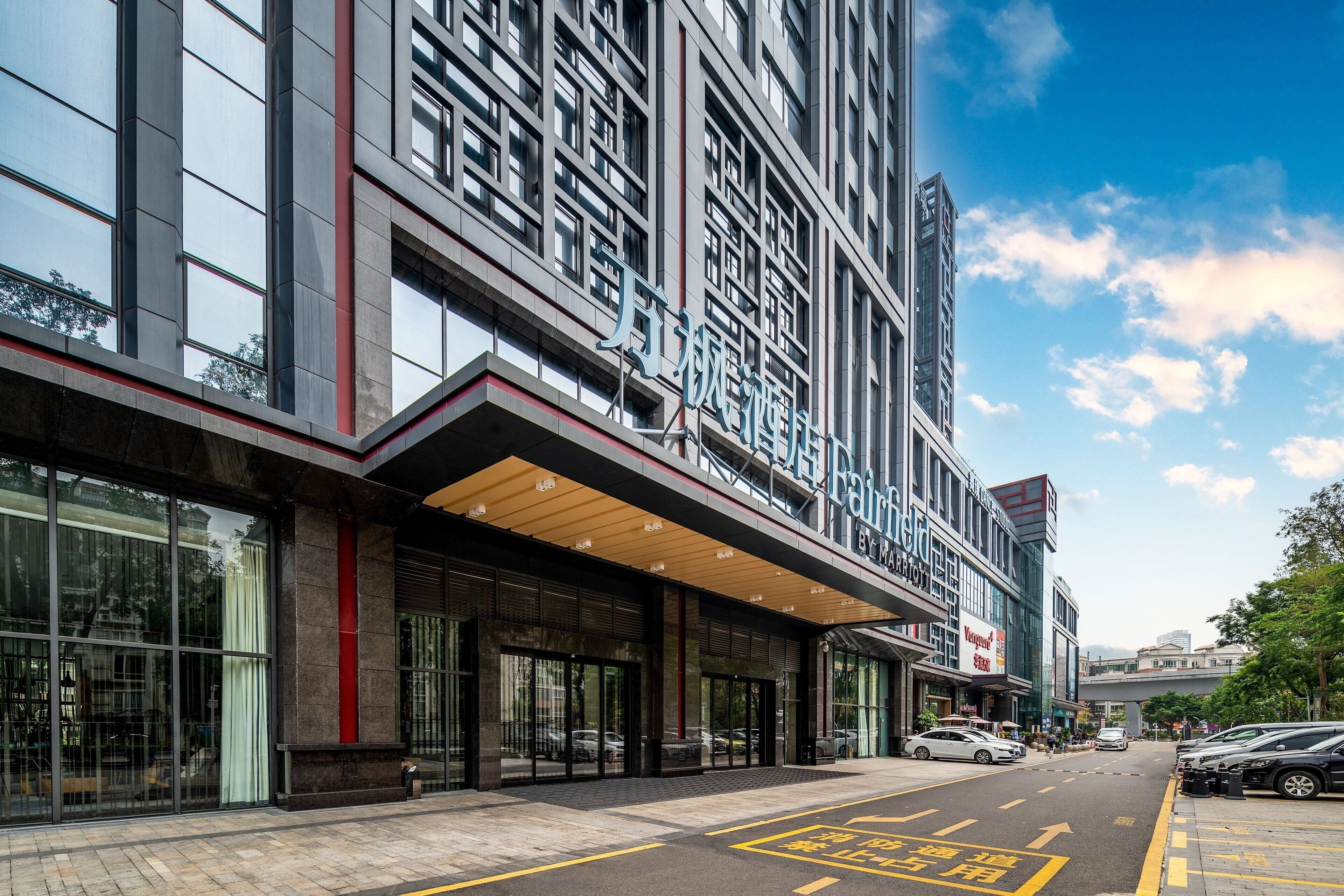A modern hotel with a prominent entrance, large windows, and a covered walkway.