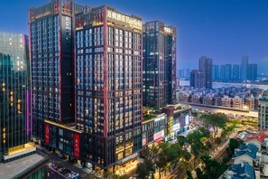 A high-rise hotel with multiple floors, large windows, and illuminated signage. - Fairfield by Marriott Zhuhai (Zhuhai)