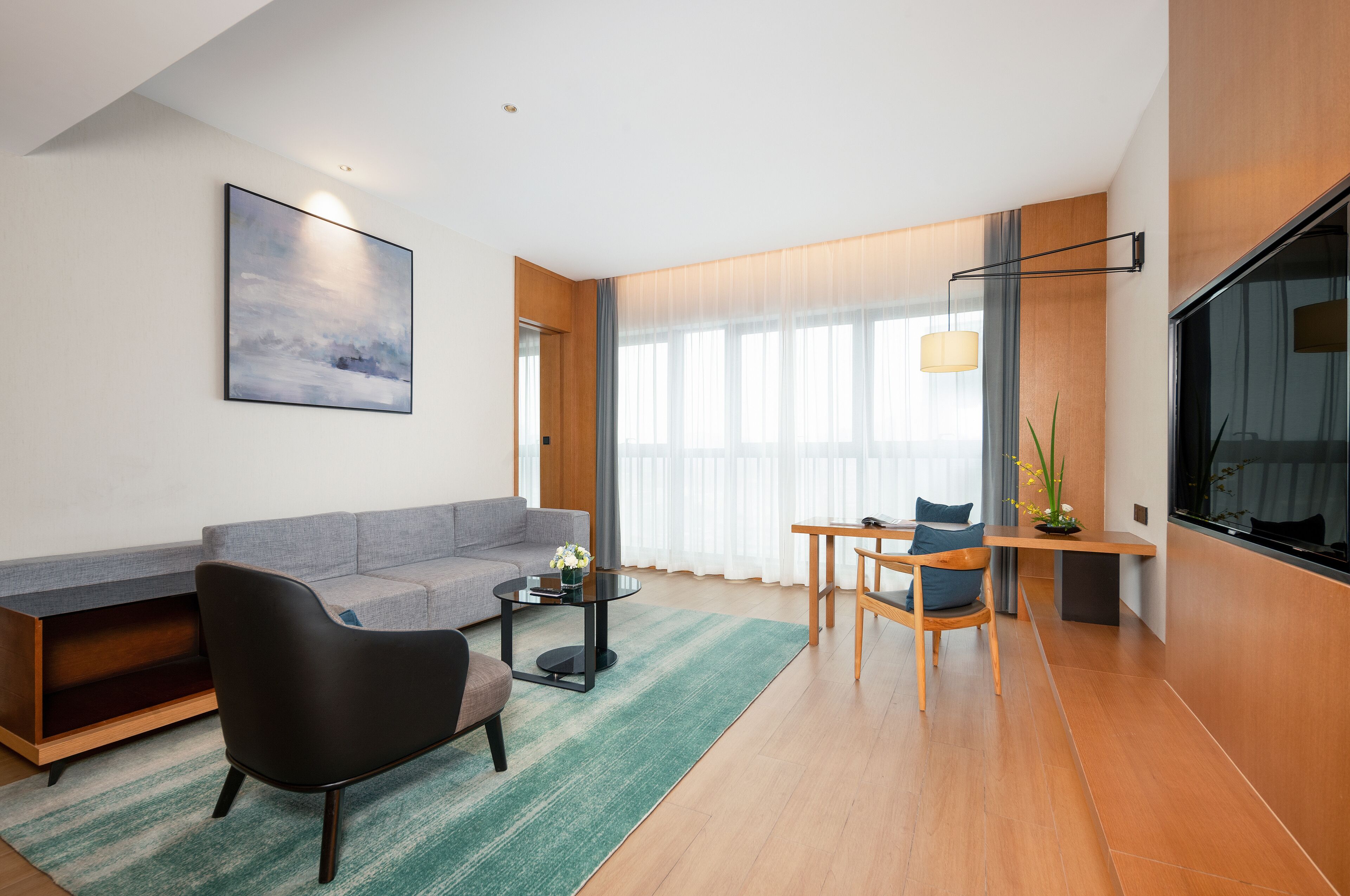 Een moderne woonkamer met een bank, fauteuil, salontafel en een eethoek met een tafel en stoelen.