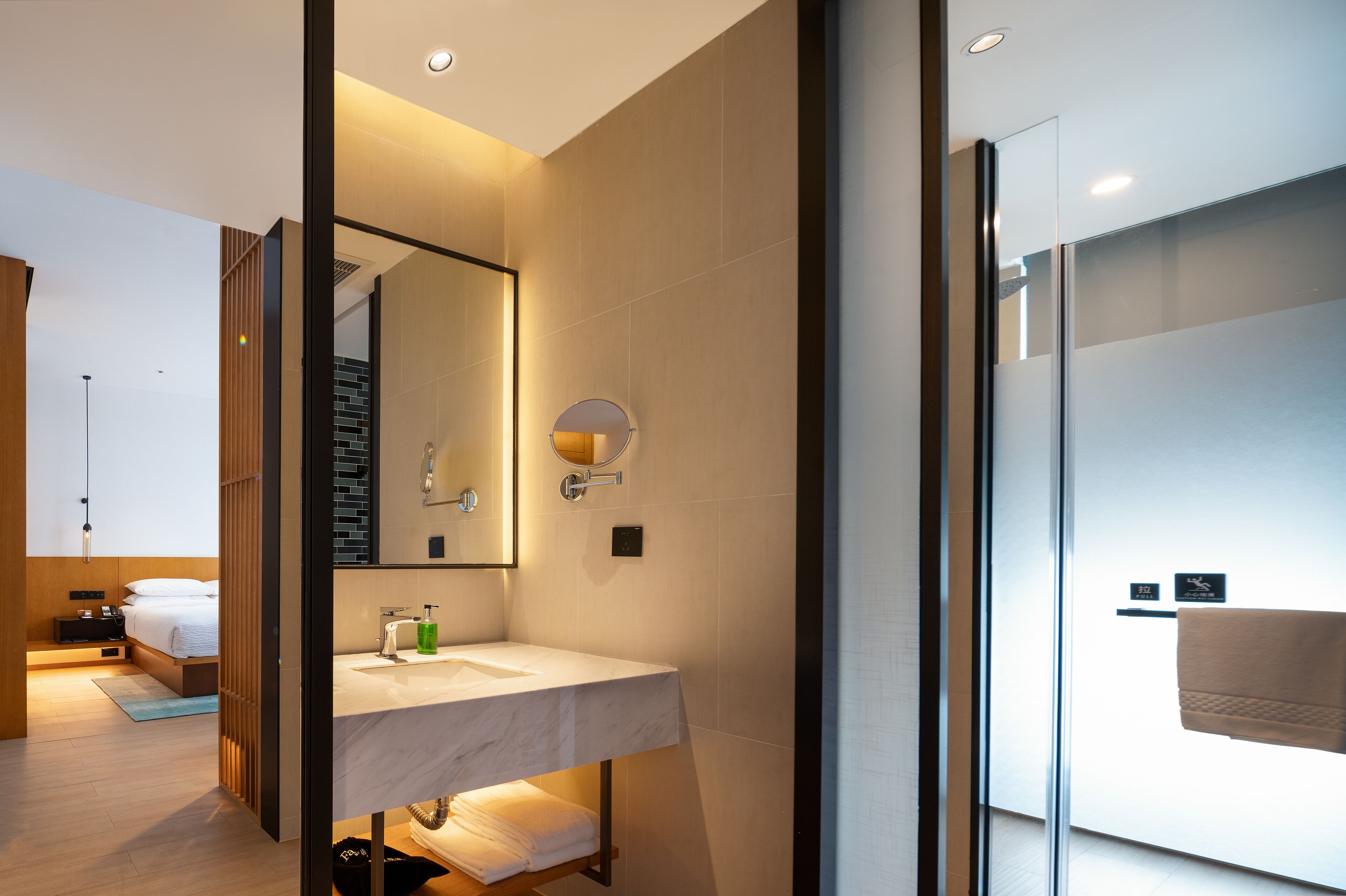 A modern bathroom with a glass shower, a marble sink, and a large mirror.