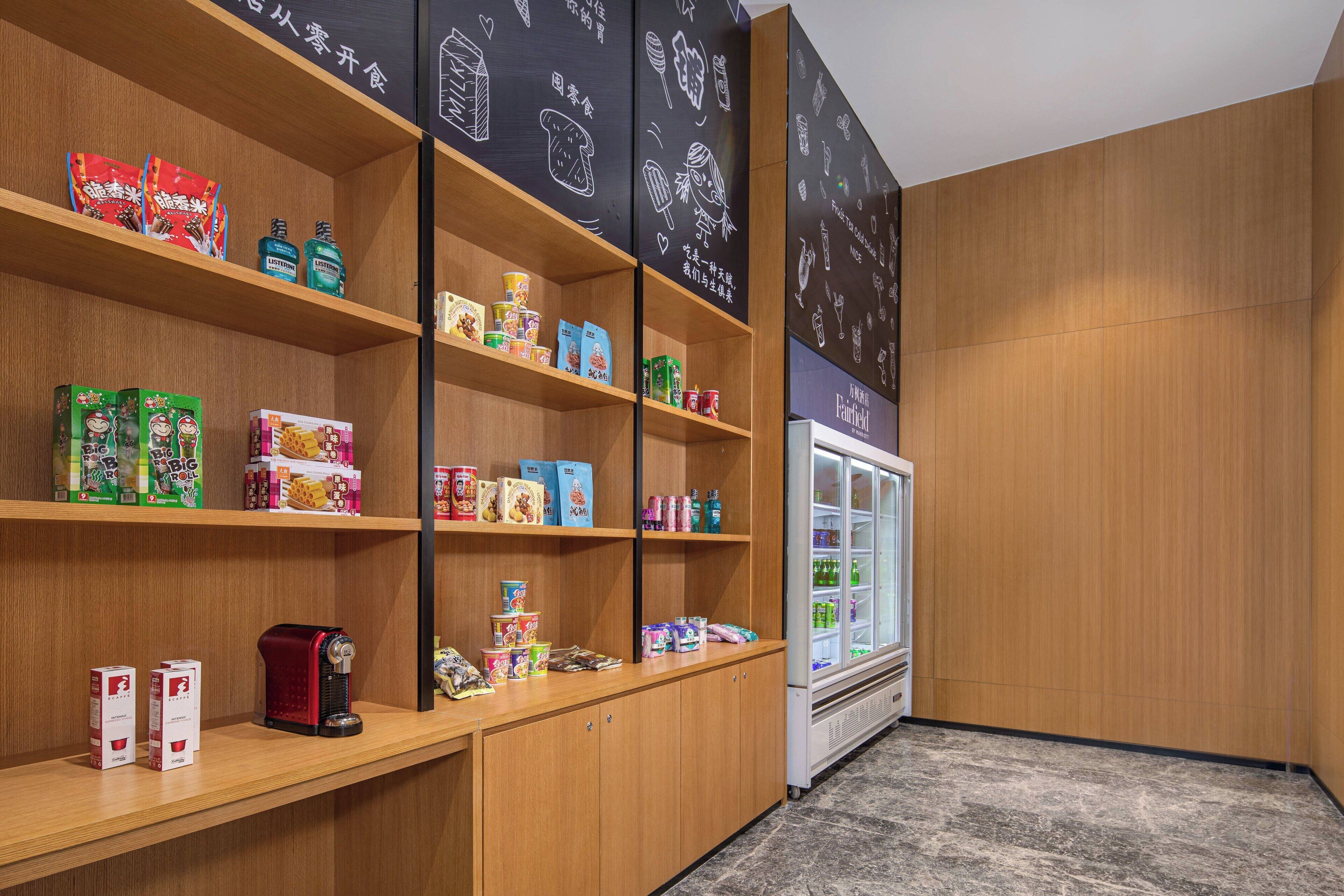 A store with shelves stocked with various food items and a refrigerated display case.