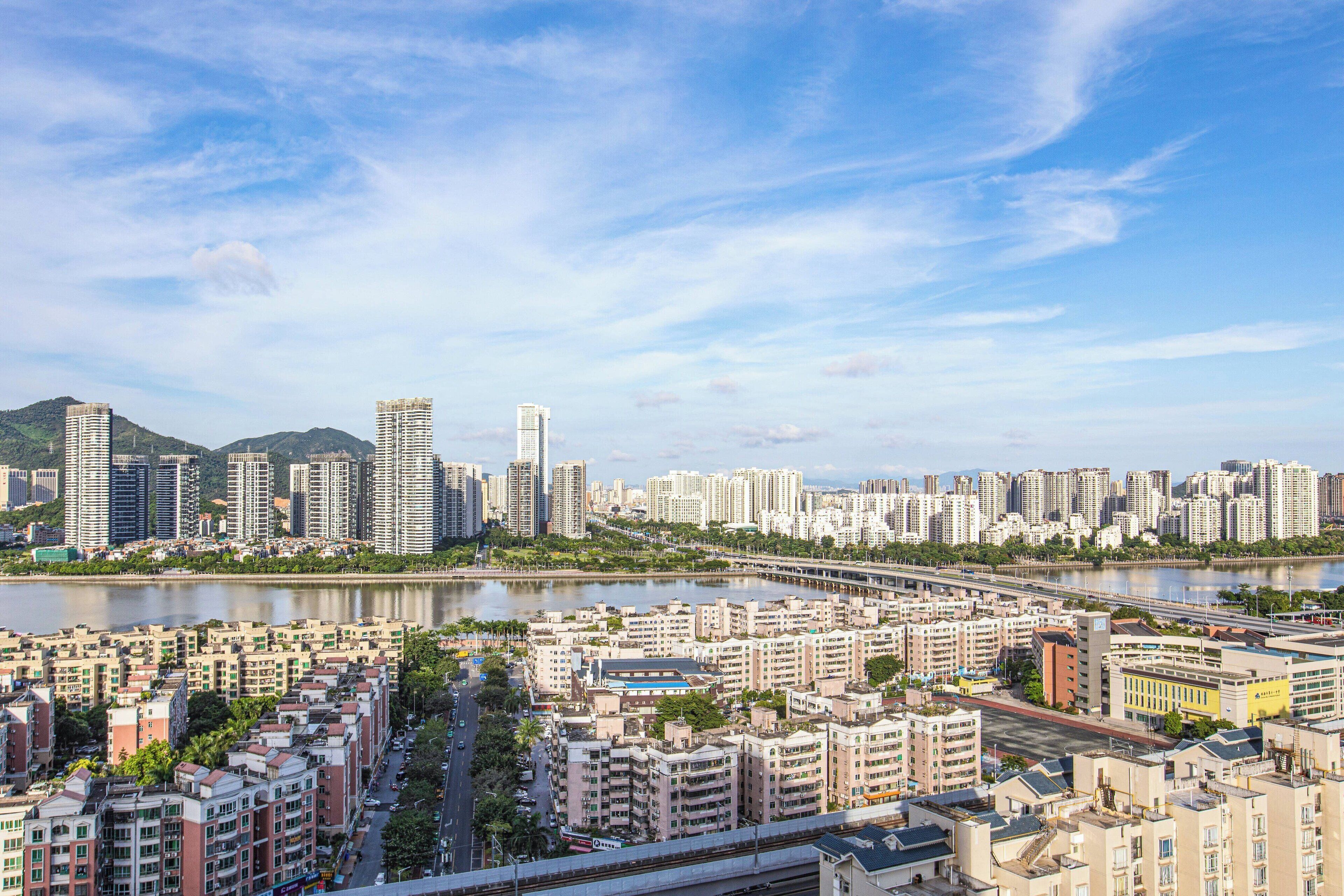 A high-rise residential area with a river and mountains in the background.