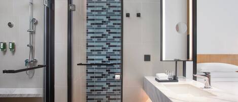A modern bathroom with a shower, a tiled wall, a sink, and a mirror.
