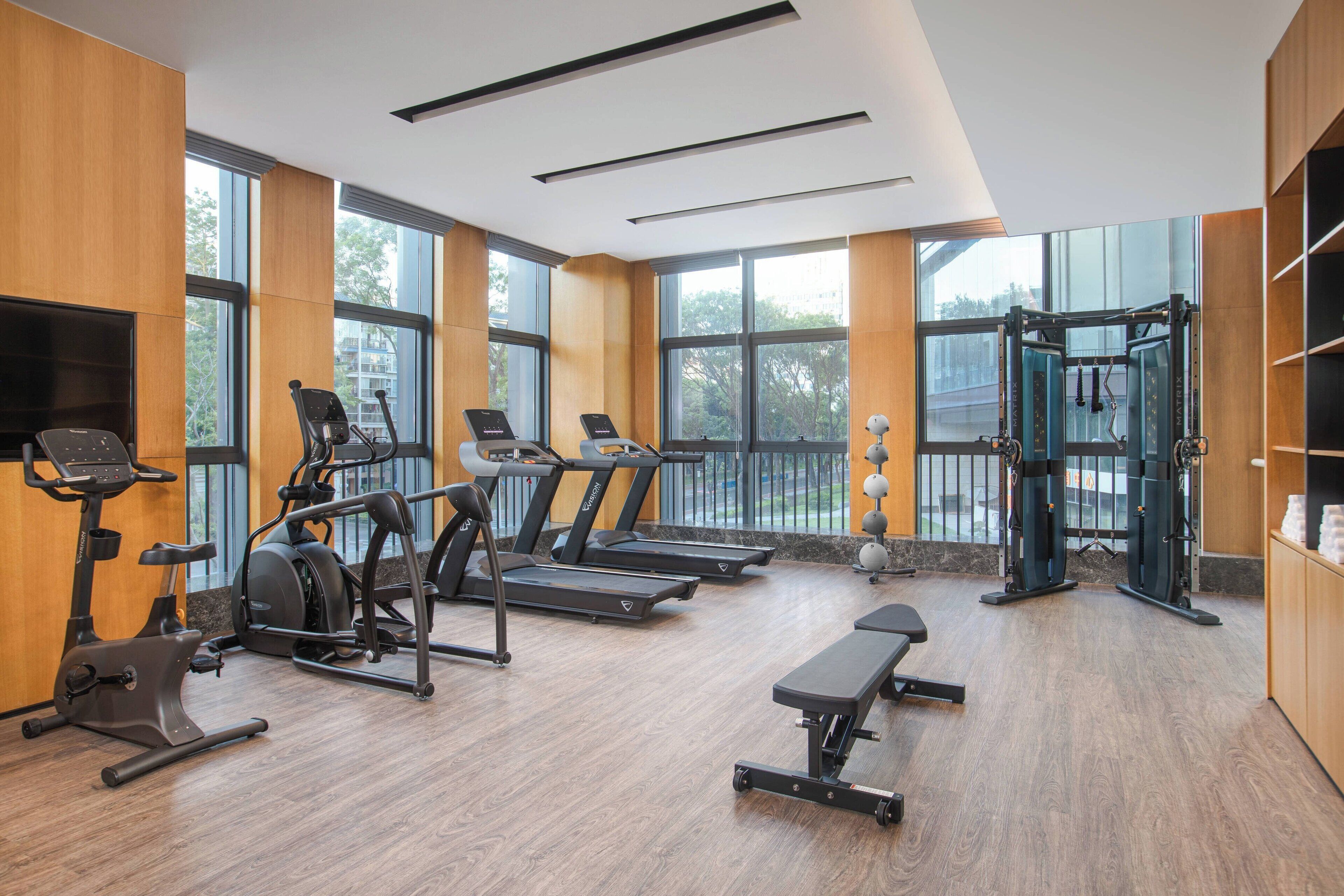 A gym with treadmills, elliptical machines, a bench, and a weight machine.