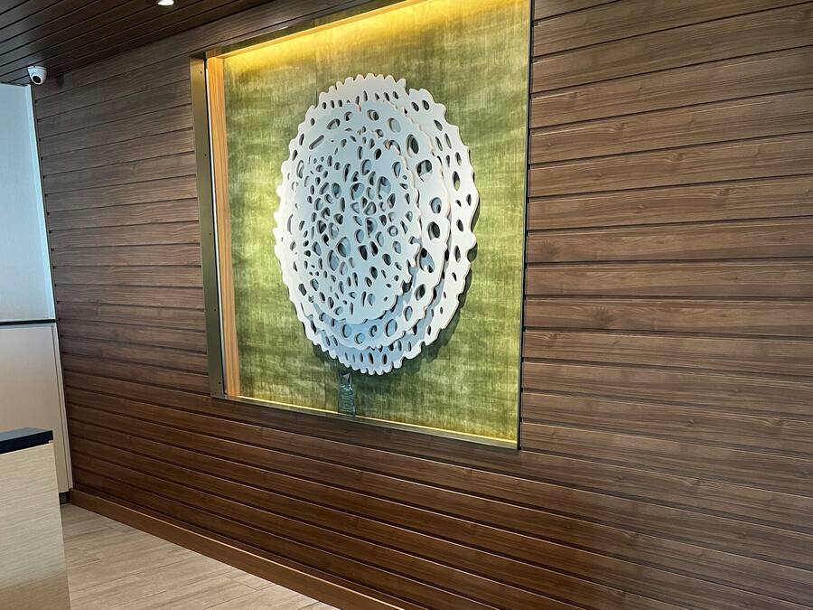 Un interior moderno con un panel de madera en la pared y una gran obra de arte circular de metal.