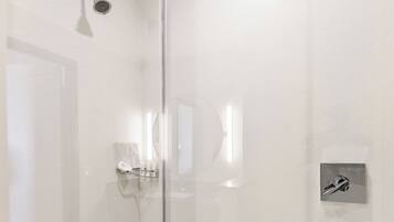 Un baño moderno con cabina de ducha de vidrio, ducha de mano y grifo empotrado.