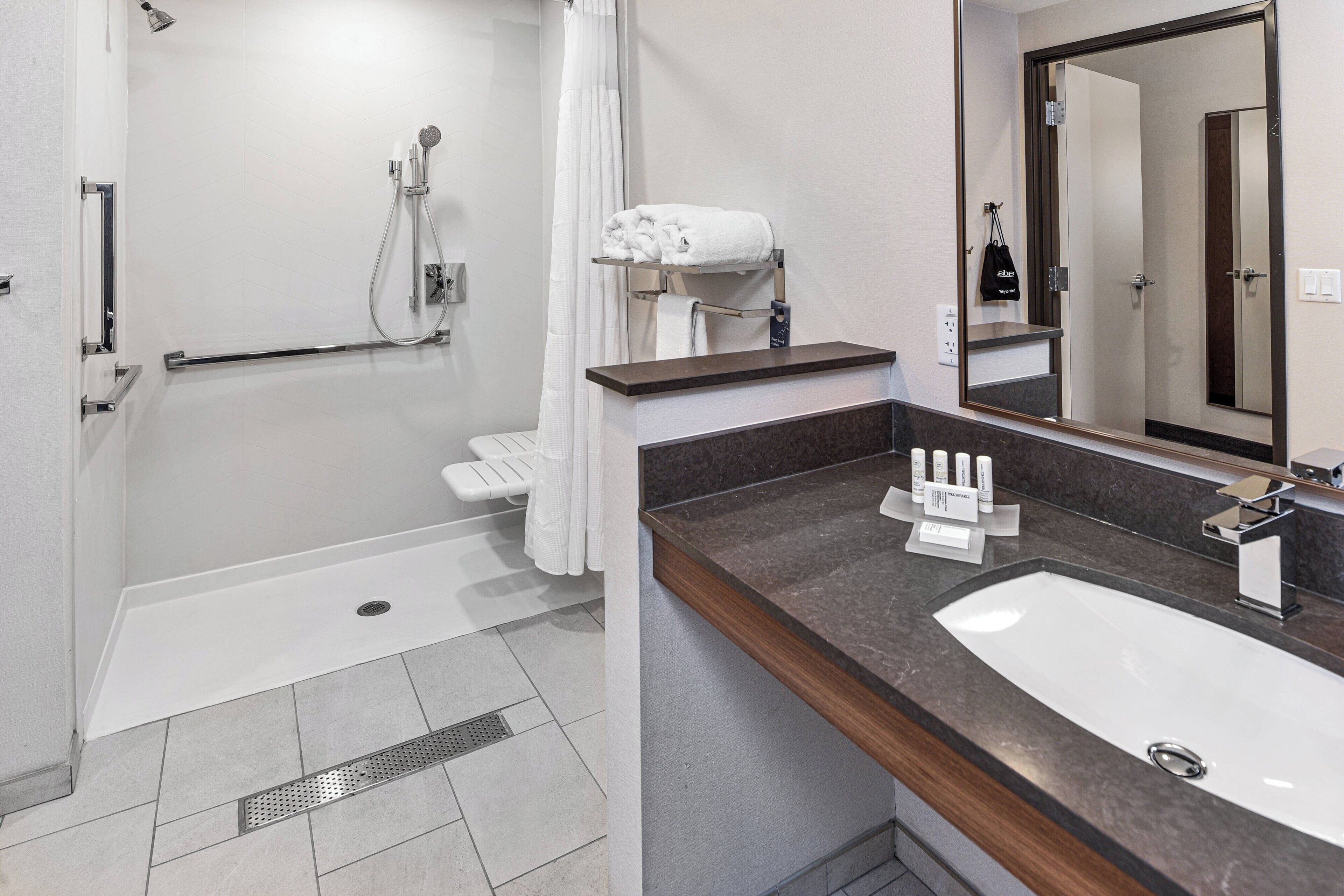 Un baño moderno con ducha, lavamanos y espejo.