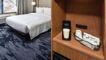 A hotel room with a neatly made bed, a coffee maker, a cup, and a tray with a bag and a box.