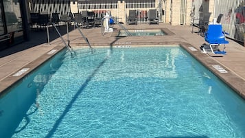 A rectangular pool with clear blue water, surrounded by lounge chairs and umbrellas. There are no diving signs visible.
