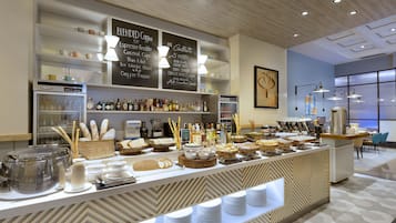 A buffet area with a variety of food and drink options, including a coffee station and a selection of beverages.