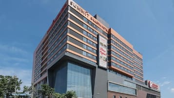 Un hotel de varios pisos con un diseño moderno, que presenta un letrero destacado que dice 'Summit' y un cartel anunciando 'Abierto ya'.