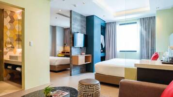 A modern hotel room with a bed, a desk, a TV, and a bathroom visible through an open door.