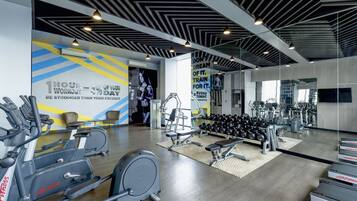 A modern gym with cardio machines, free weights, and motivational posters.