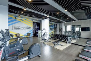Un gimnasio moderno con máquinas de cardio, pesas libres y carteles motivacionales.