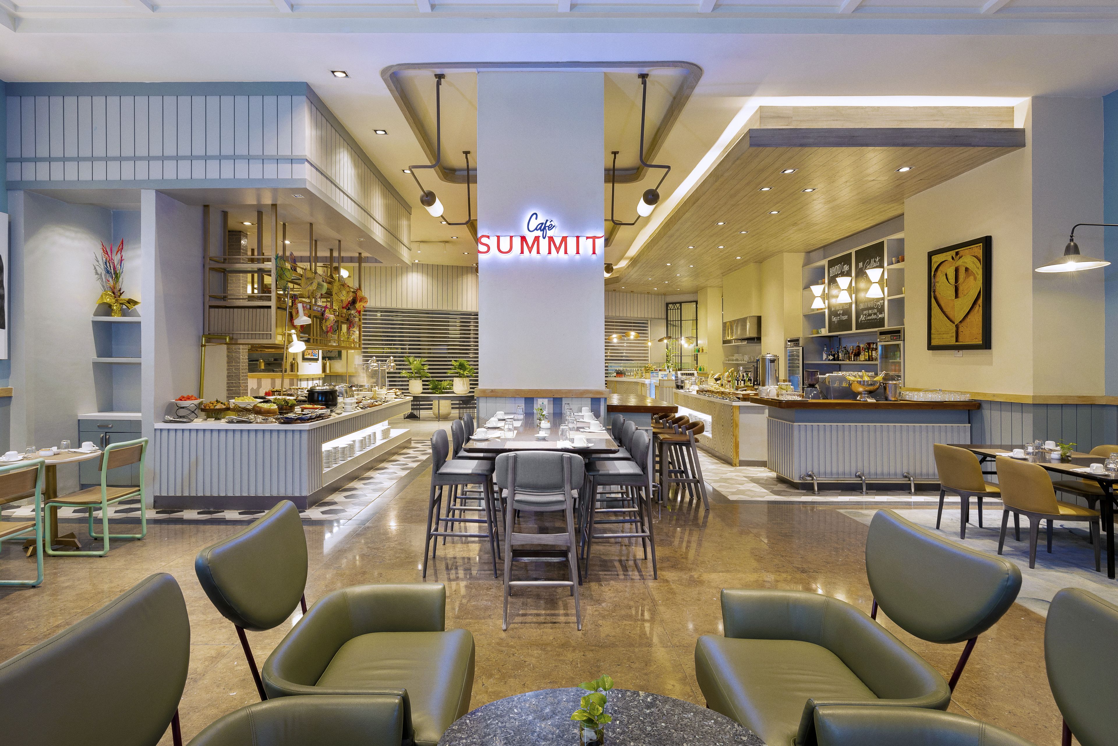 A modern cafe with a central seating area, a bar, and a variety of food displays.