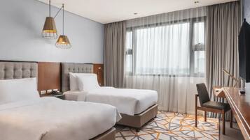 A hotel room with two beds, a desk, and a chair.