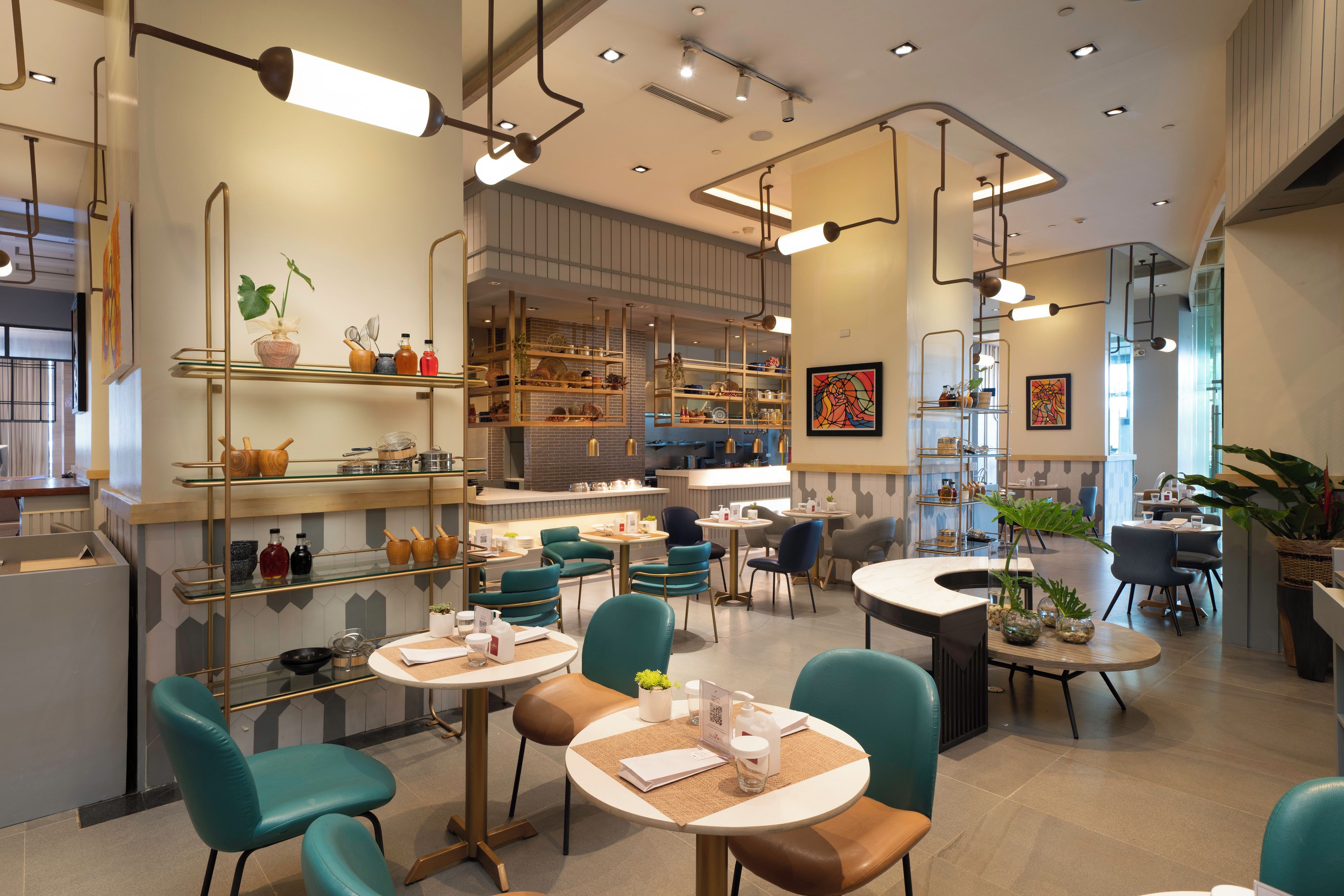 Un interior de restaurante moderno con sillas color turquesa, mesas redondas y una variedad de platos exhibidos en estanterías.
