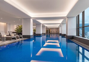 A modern indoor swimming pool with clear blue water, sunlit ceiling, and a view of the city through large windows. - Summit Galleria Cebu (Cebu City)