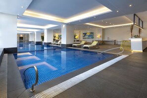 A modern indoor swimming pool with lounge chairs, a reception area, and a bar. - Summit Galleria Cebu (Cebu City)