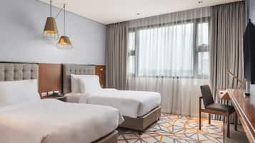 A hotel room with two beds, a desk, and a chair.